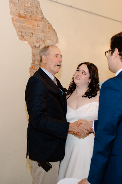 a bride and groom having a moment with an elderly man during their reception