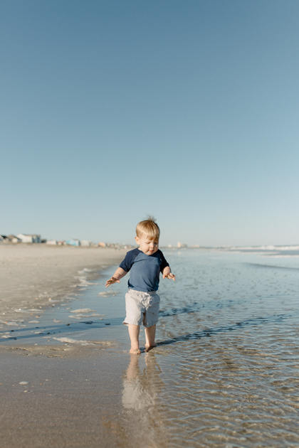 a young boy running in myrtle beach water during family photos